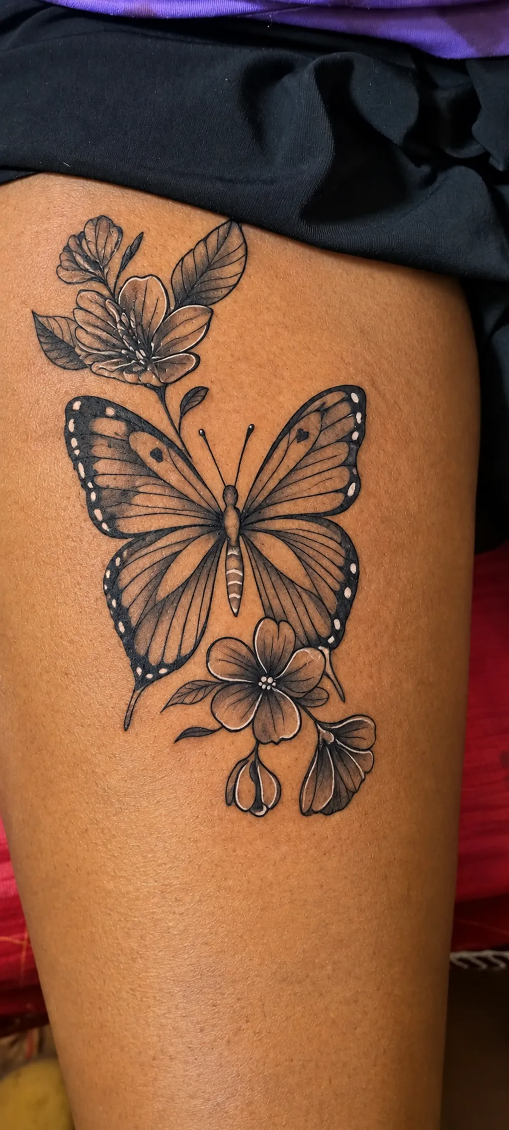 Black and grey butterfly and floral upper-thigh tattoo by Jay at Inking Tattoos in Limuru, Kenya